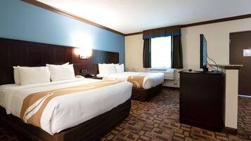 A hotel room with two beds, a desk, and a television.