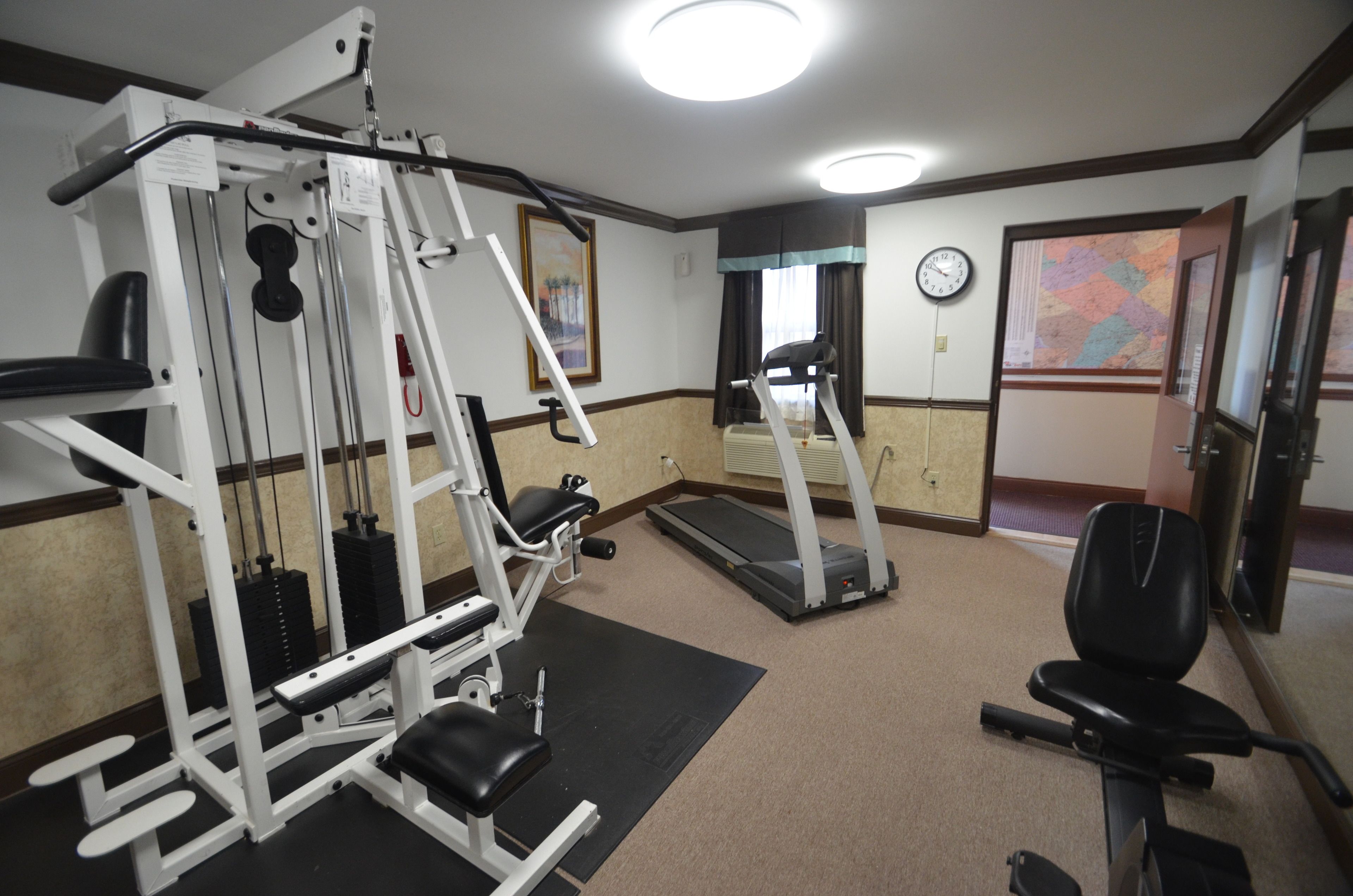 Et fitnesscenter med forskellig træningsudstyr, heriblandt en bænkpres, løbebånd og en motionscykel.