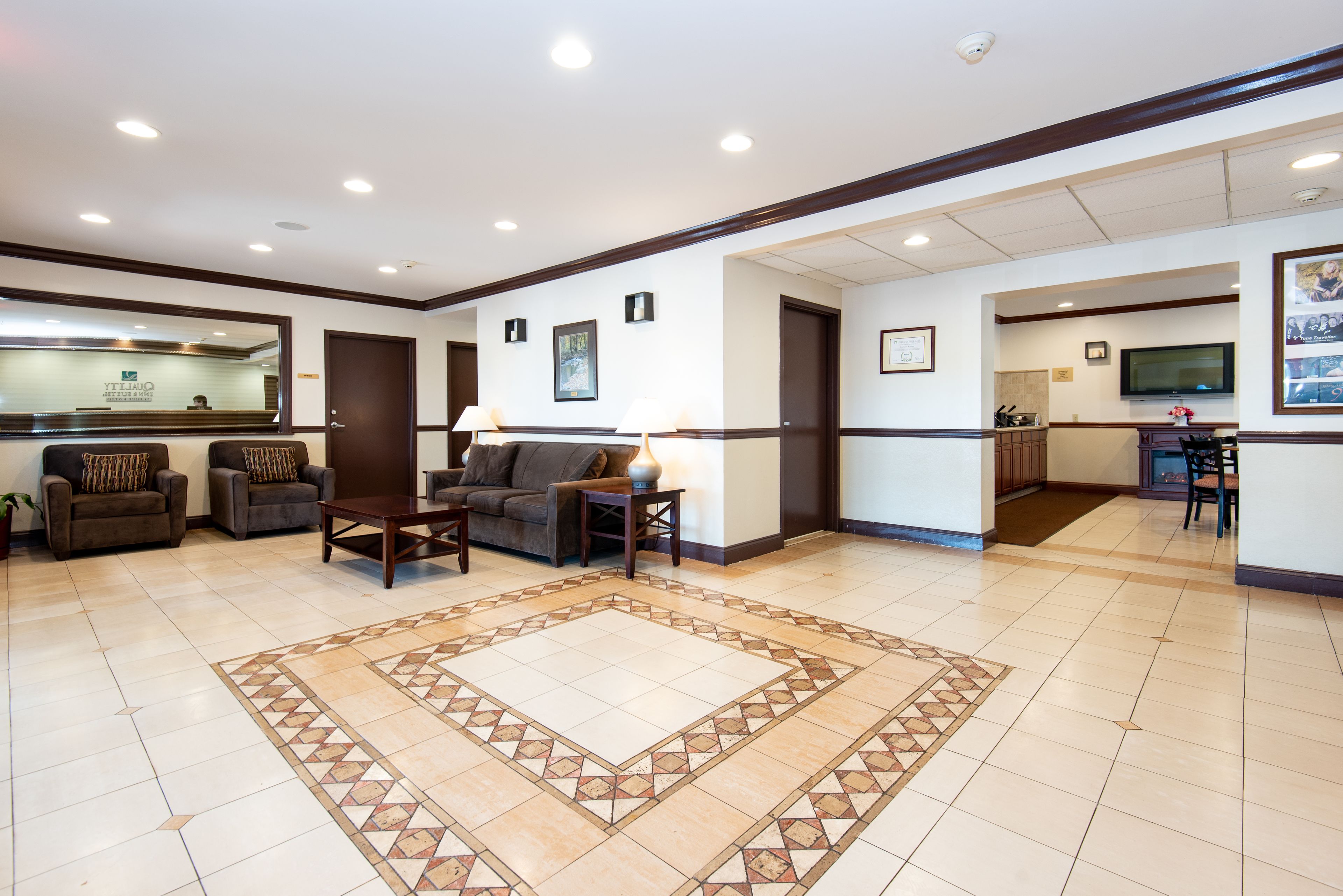 A spacious lobby with a reception desk, comfortable seating, and a tiled floor.