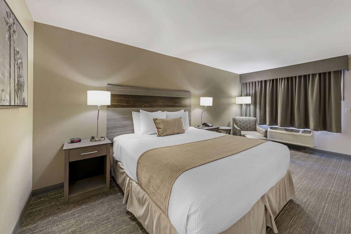A hotel room with a large bed, bedside tables, a desk, and a chair.
