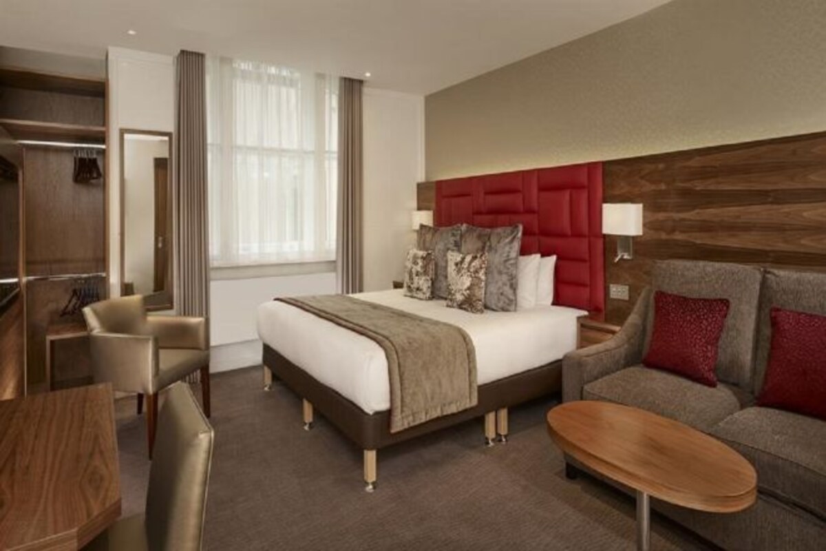Une chambre d’hôtel avec un lit, un canapé, un bureau et une chaise.