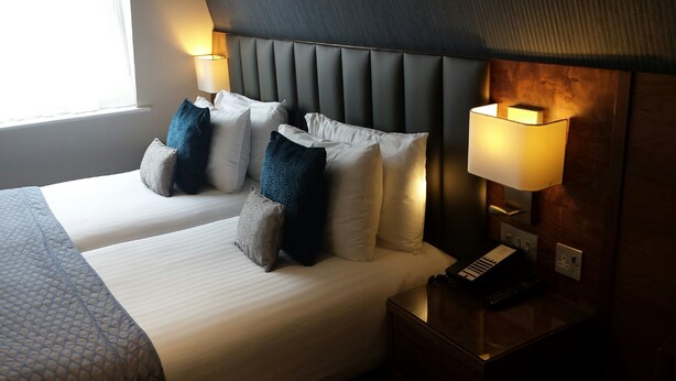 Ein Hotelzimmer mit einem großen Bett, zwei Nachttischlampen und einem Telefon am Nachttisch.