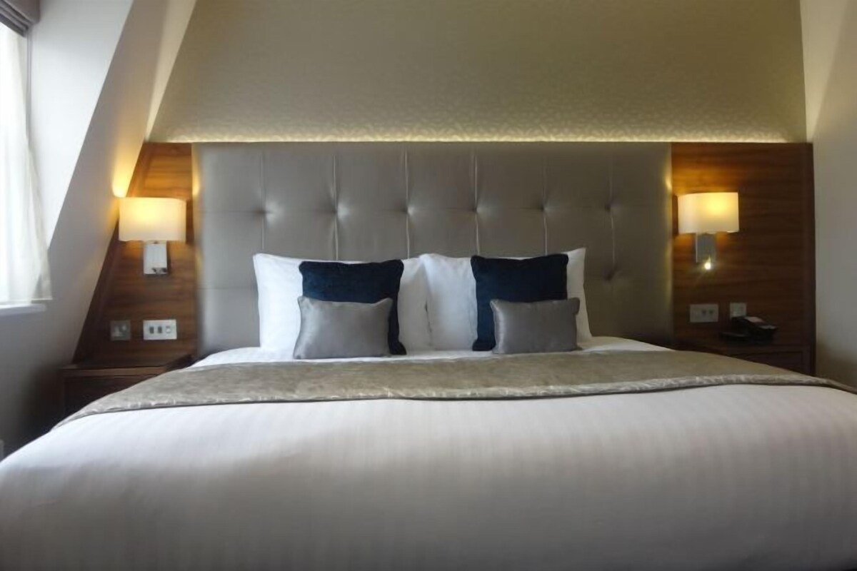 Ein Hotelzimmer mit einem großen Bett, zwei Nachttischlampen und einem Holzkopfstück.