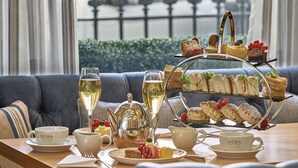 Ein Tisch, gedeckt mit Teetassen, einem Teekessel, einer Etage mit Desserts sowie verschiedenen Sandwiches und Gebäck.
