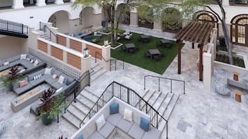 A courtyard with outdoor seating, a pergola, and a staircase leading to an upper level.