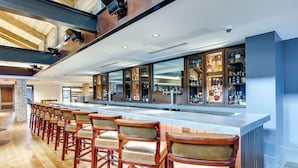 Een bar met een lange toonbank en meerdere krukken.