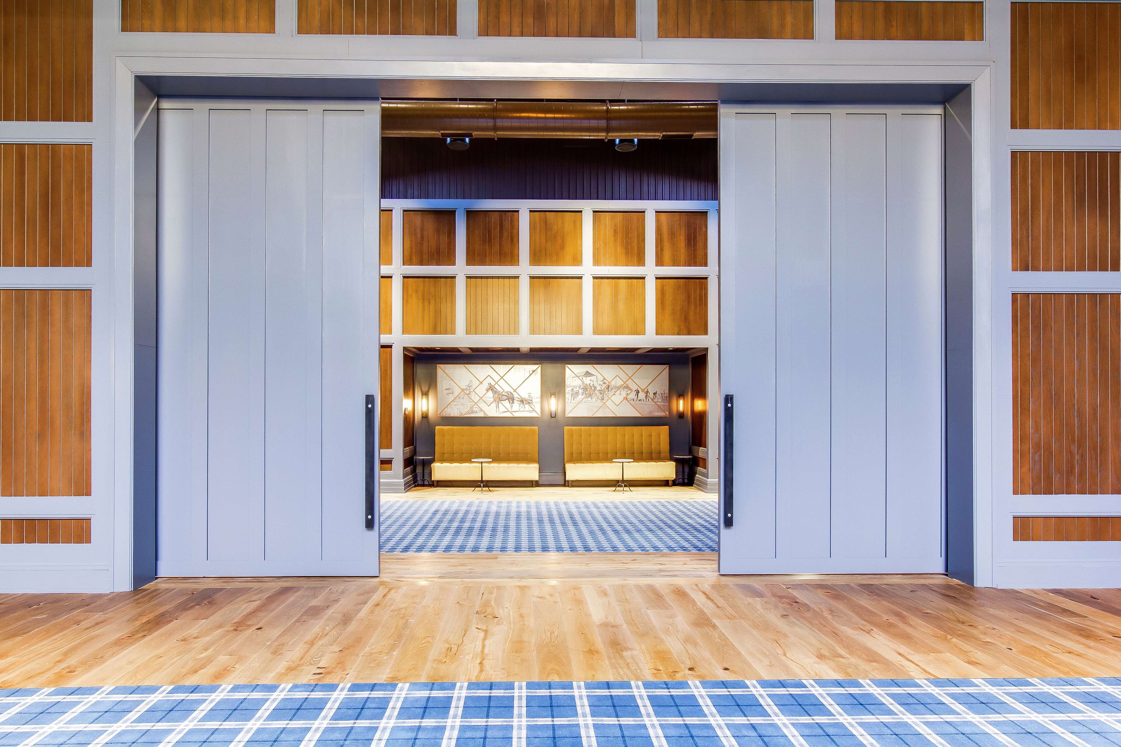 Un hall d’hôtel avec un sol à carreaux, un comptoir d’accueil et un espace salon agrémenté d’un mur à motifs.