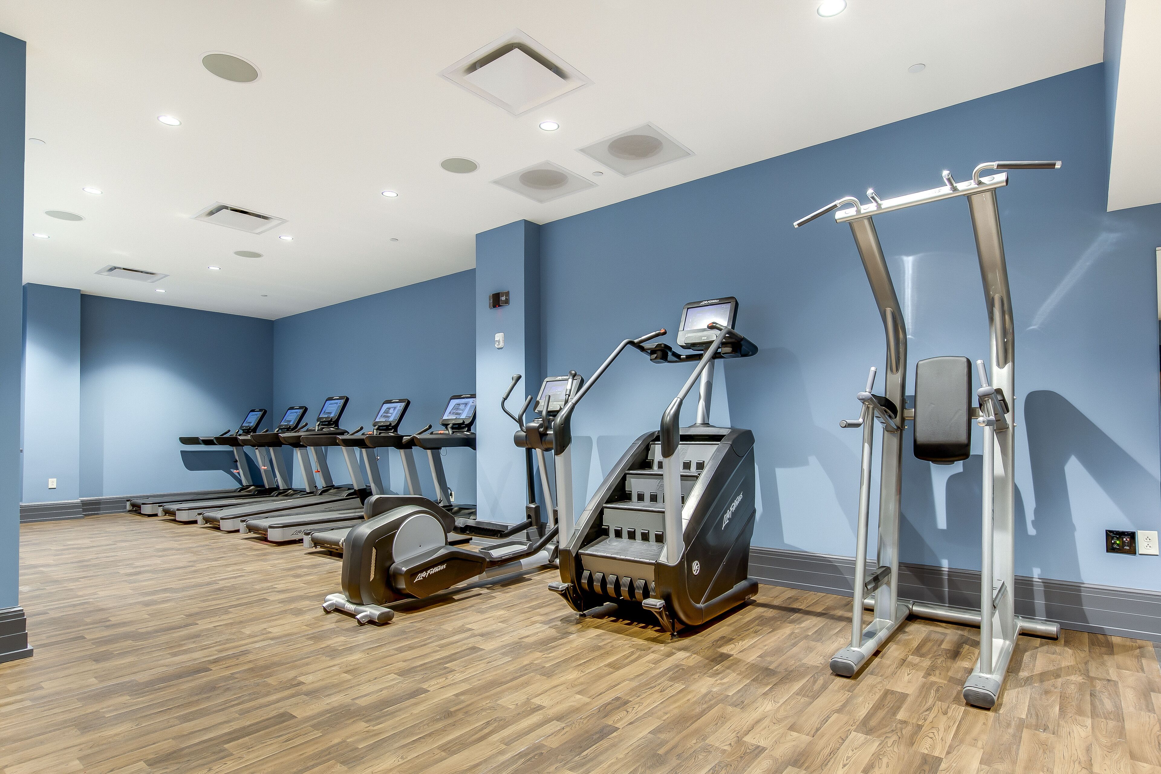 A gym with multiple treadmills, elliptical machines, and a stair climber.