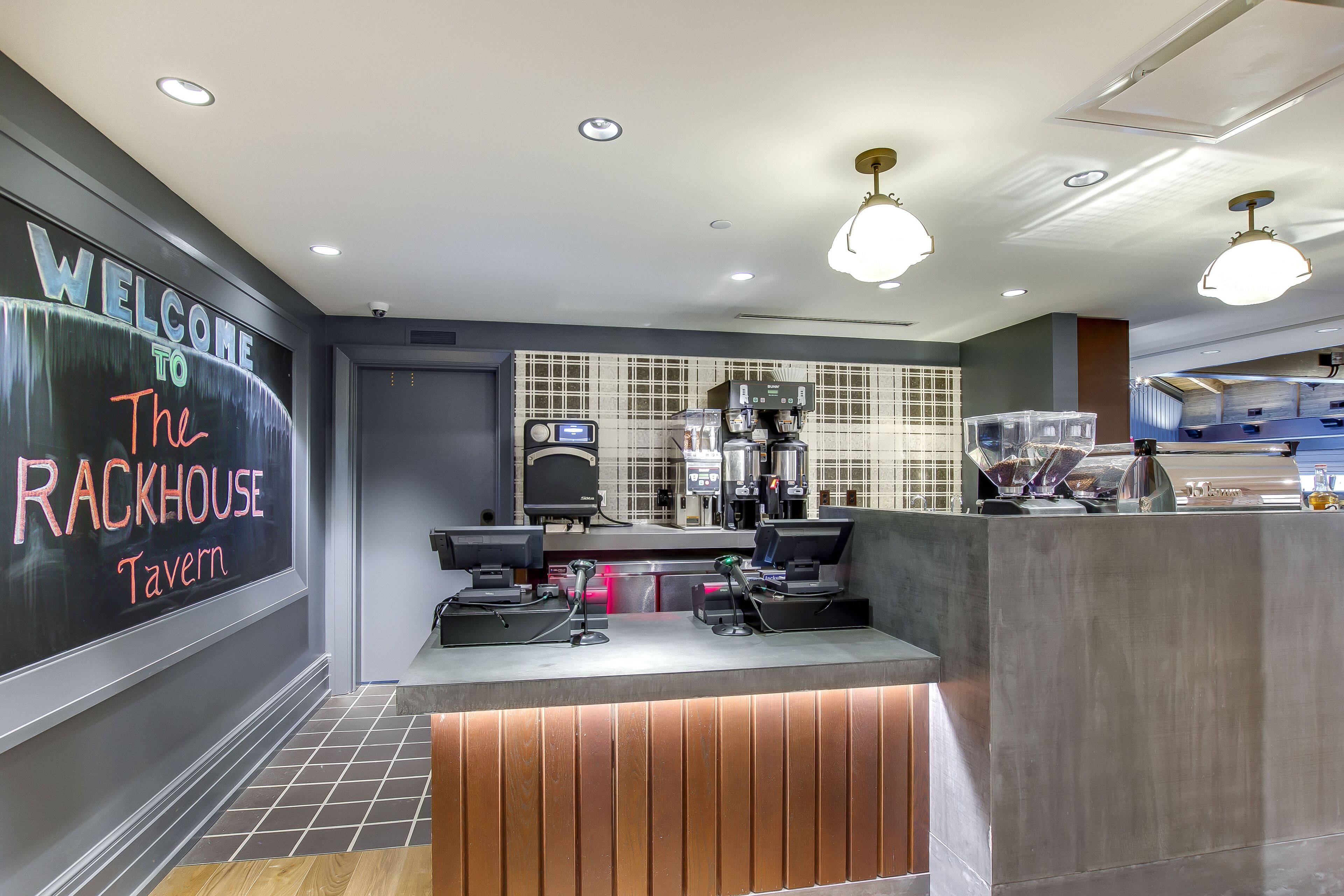 A modern reception area with a welcome sign, a counter with coffee machines, and a tiled backsplash.