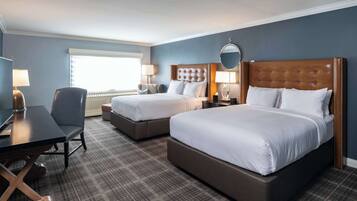 A hotel room with two beds, a desk, and a chair.