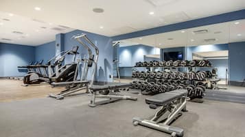 Un gimnasio moderno con máquinas de cardio, bancos de pesas y una estructura con mancuernas.