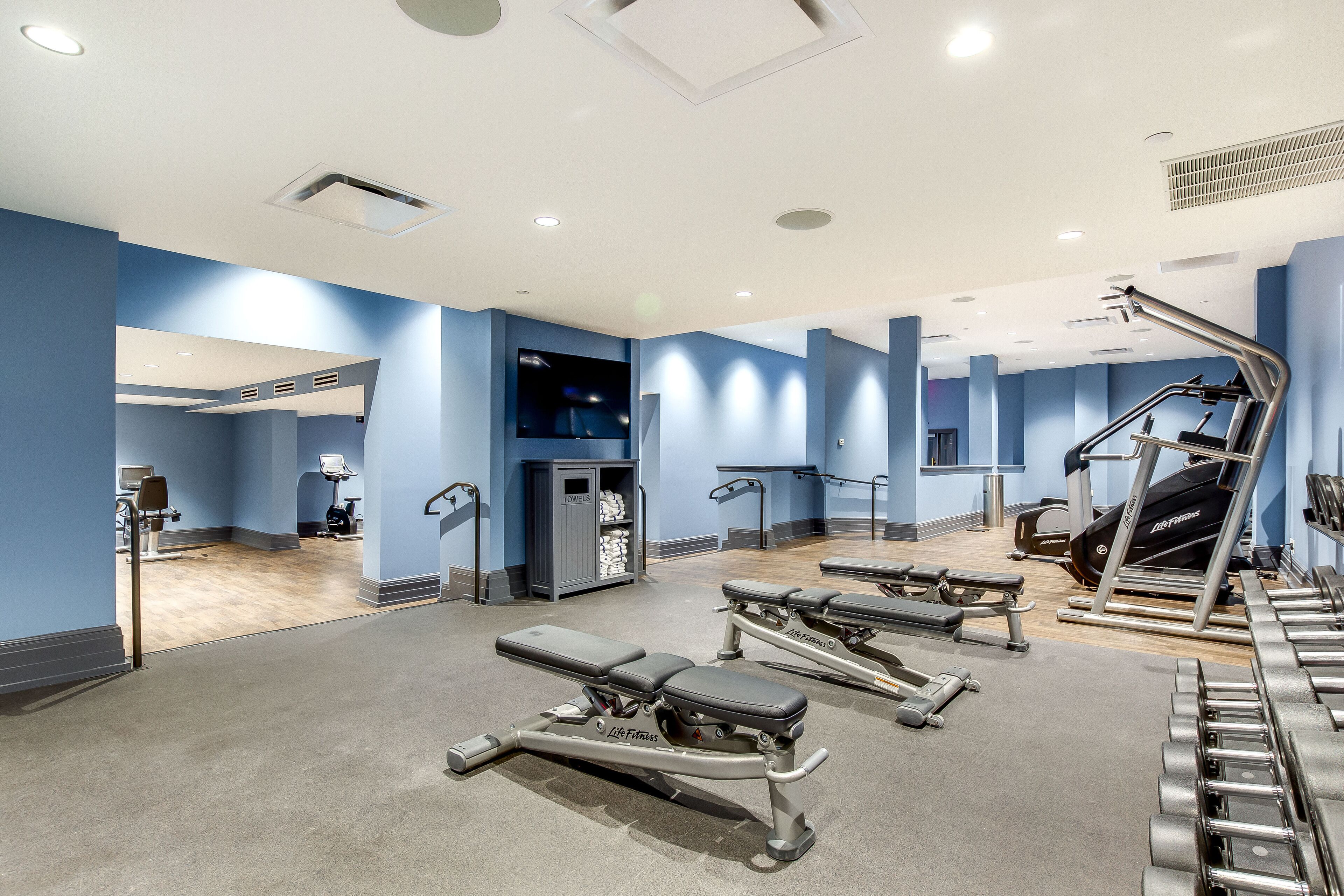 A gym with exercise equipment, a television, and a towel storage area.