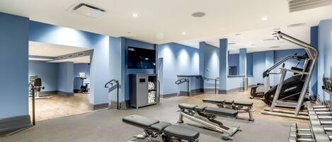 A gym with exercise equipment, a television, and a towel storage area.