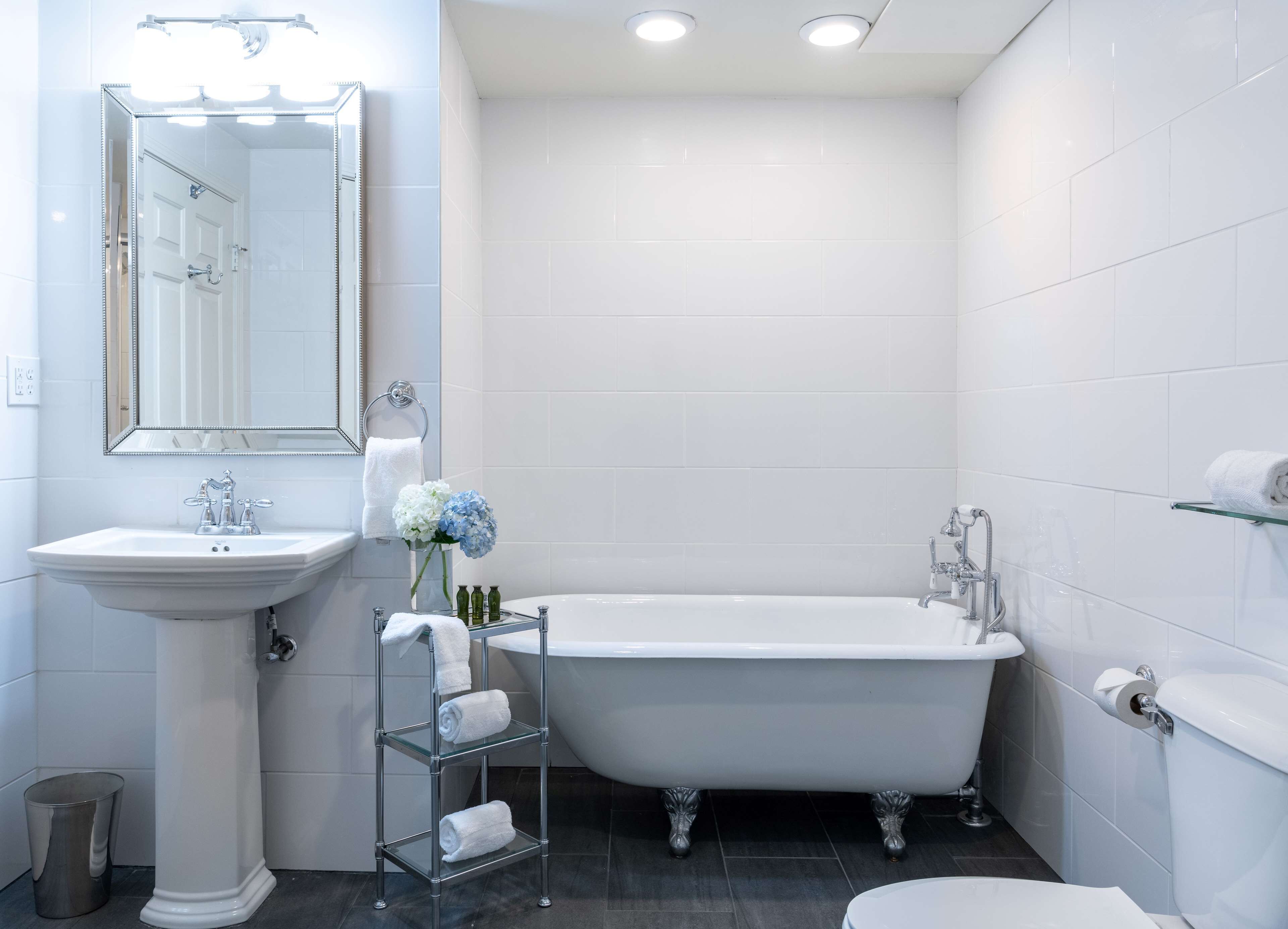 A modern bathroom with a freestanding bathtub, a pedestal sink, and a vanity mirror.