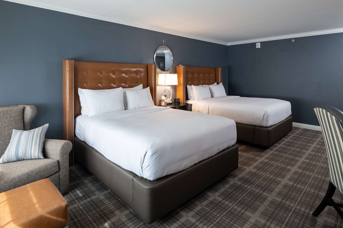 Habitación de hotel con dos camas, un sofá, una silla y una mesita.