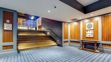 A hotel lobby with a checkered floor, wooden panel walls, a staircase, and a reception desk.