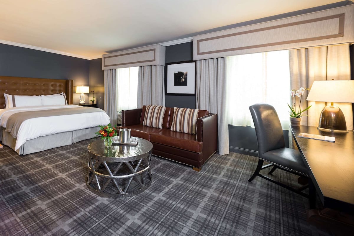 Una habitación de hotel con cama, sofá, mesa de centro redonda, escritorio y silla.