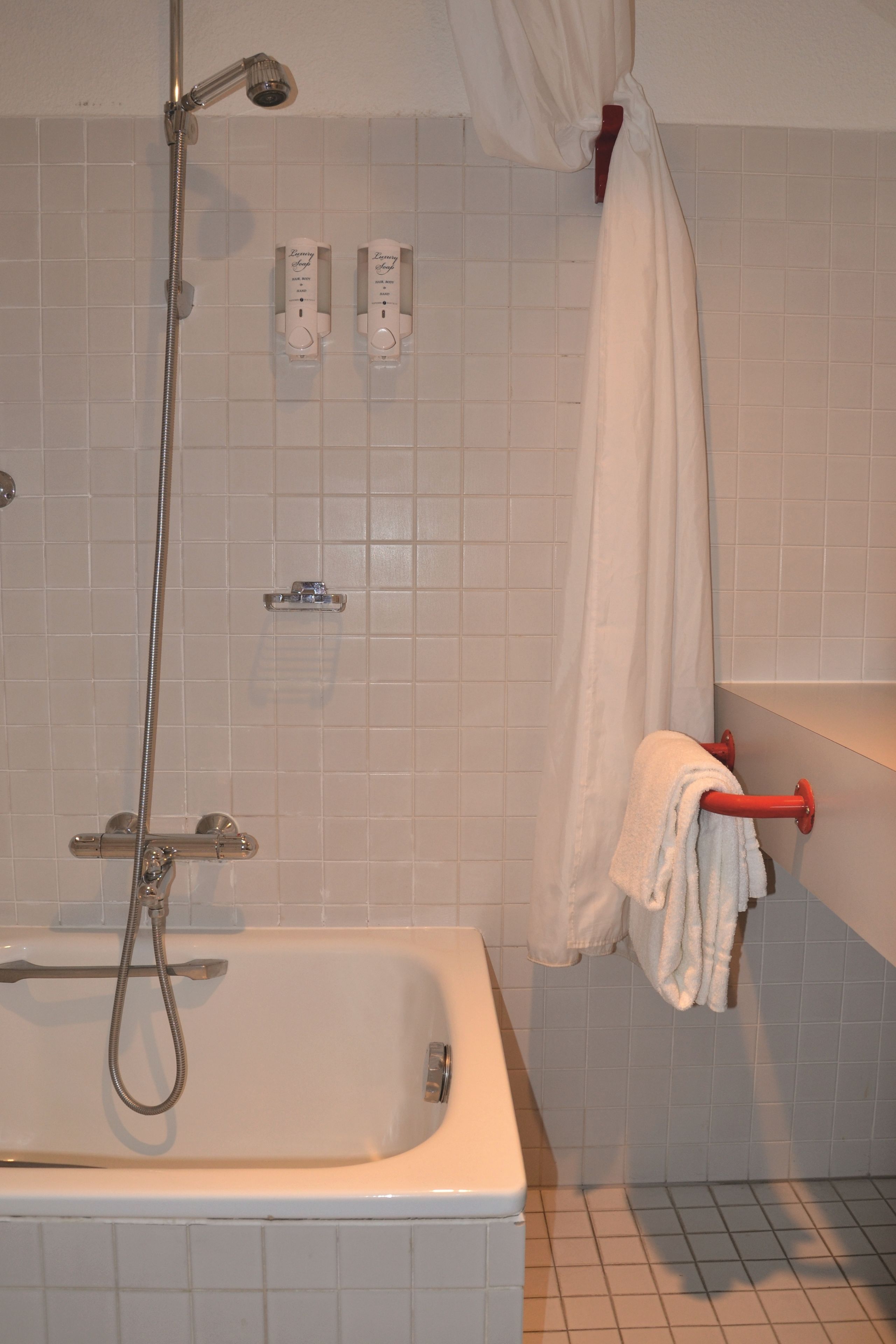 A bathroom with a bathtub, a showerhead, and a towel rack.