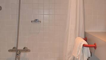 A bathroom with a bathtub, a showerhead, and a towel rack.