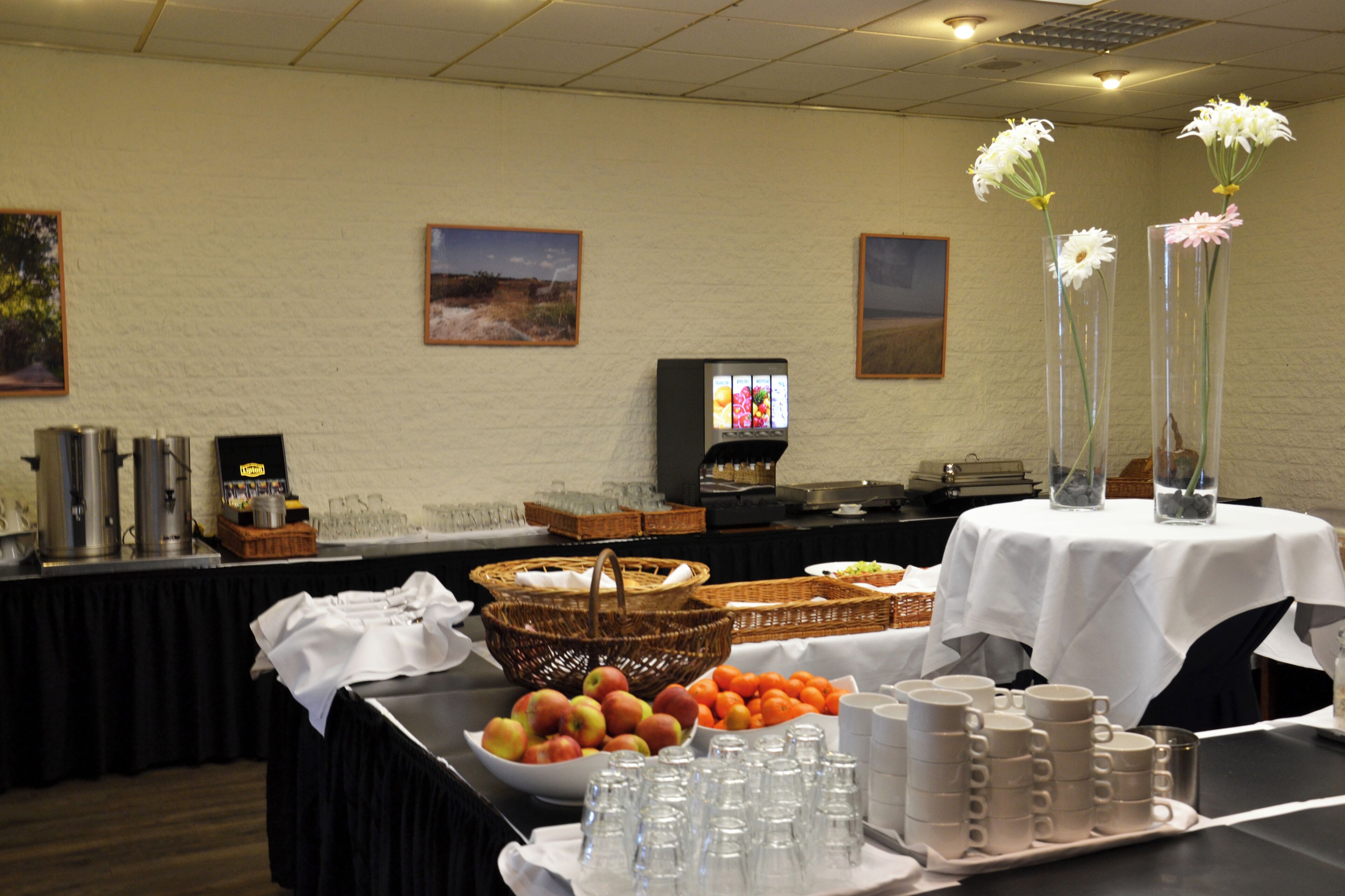 A buffet setup with a variety of food items, a television, and decorative flowers.