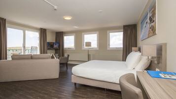 A hotel room with a bed, a sofa, a desk, and a TV.