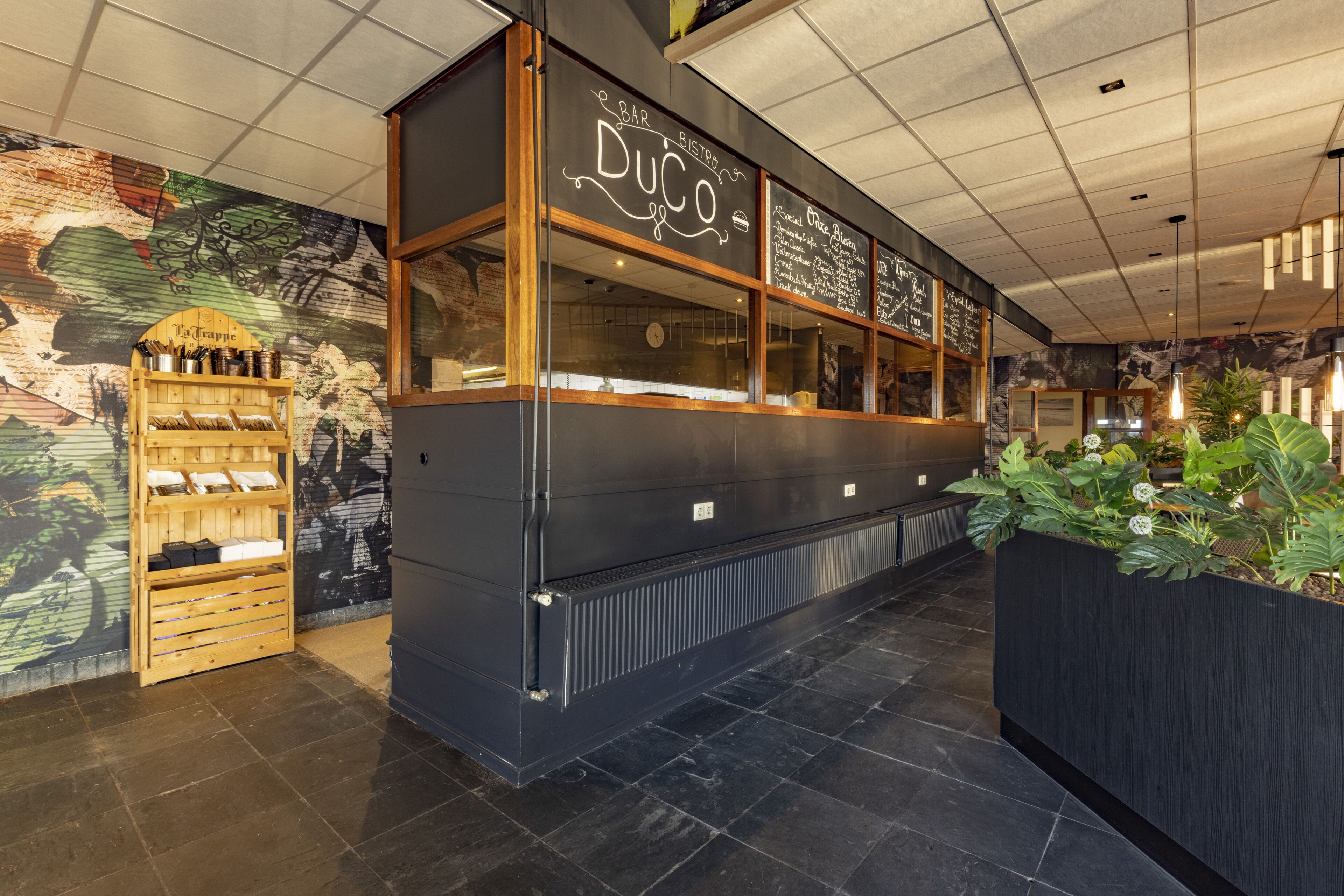 En restaurang med en svart fasad, trädetaljer i inredningen och en meny som är skriven på en svart tavla.