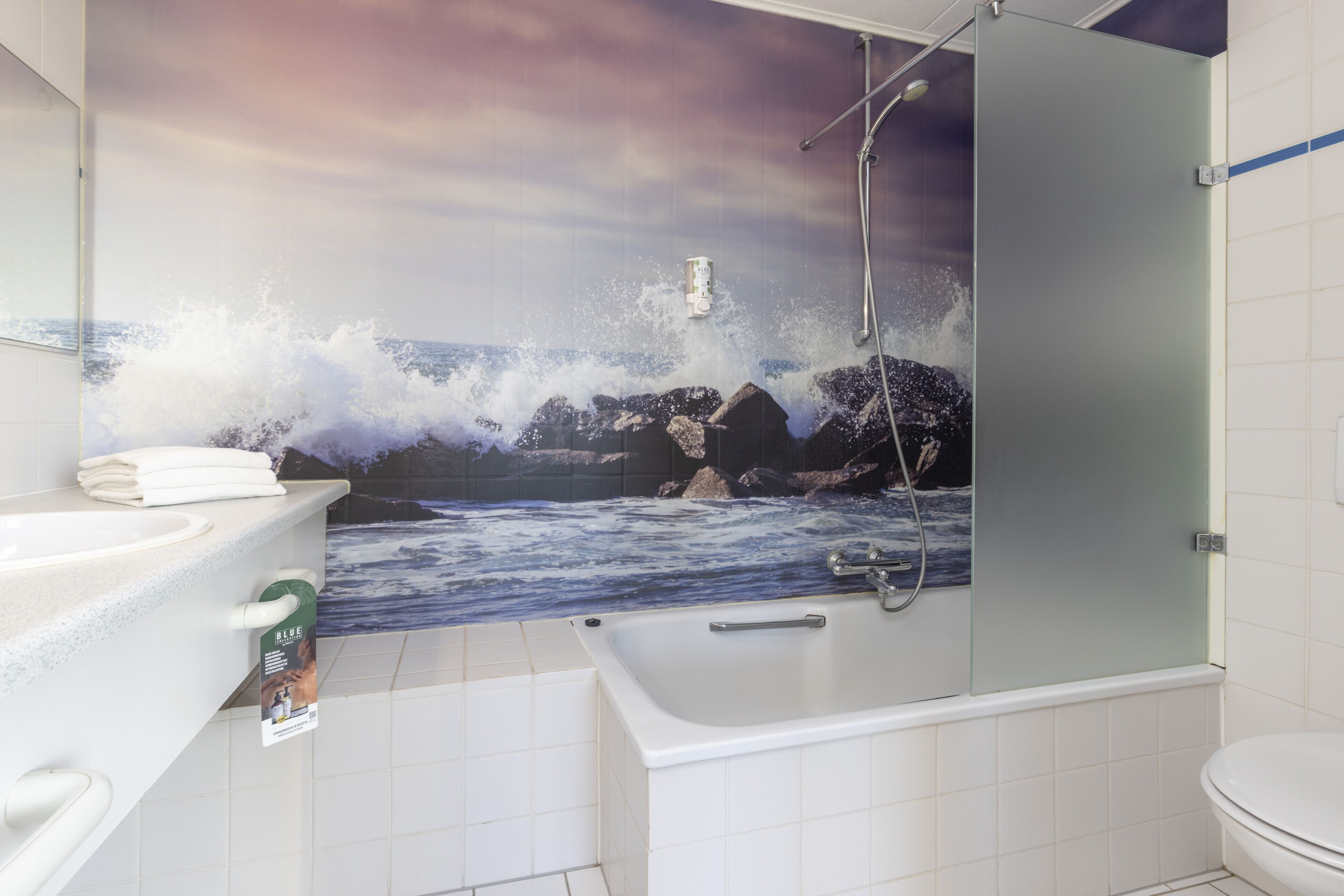 Ein Badezimmer mit Meereswandgemälde, einer Badewanne und einer Dusche.