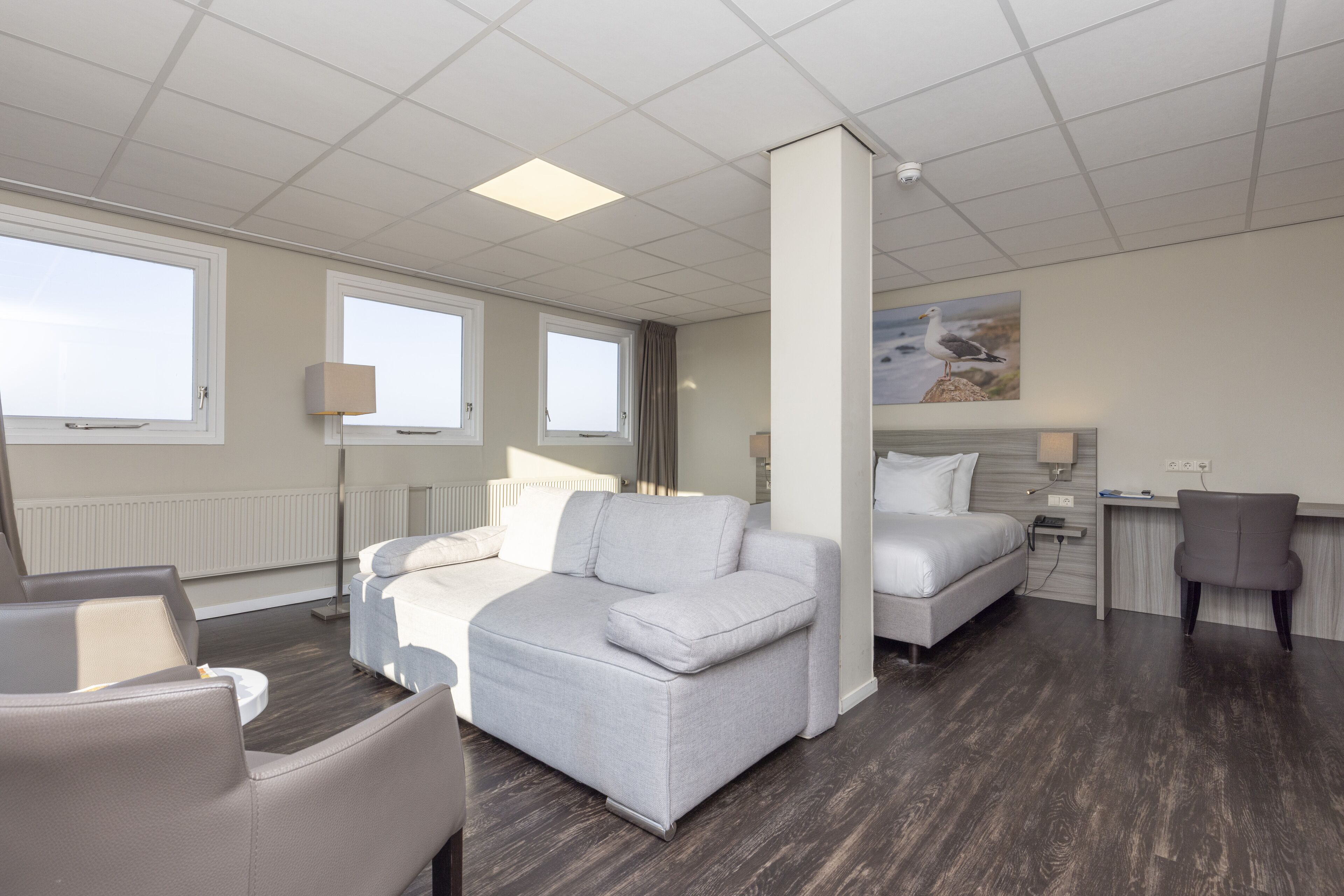 Une chambre d’hôtel moderne équipée d’un canapé, d’un lit, d’un bureau et d’une chaise.