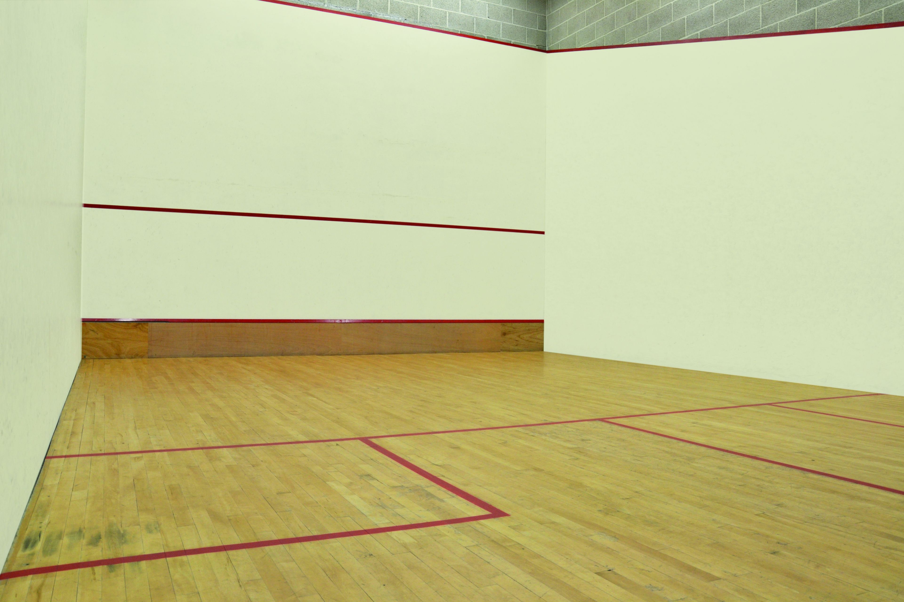 Een squashbaan met houten vloer en rode lijnen.