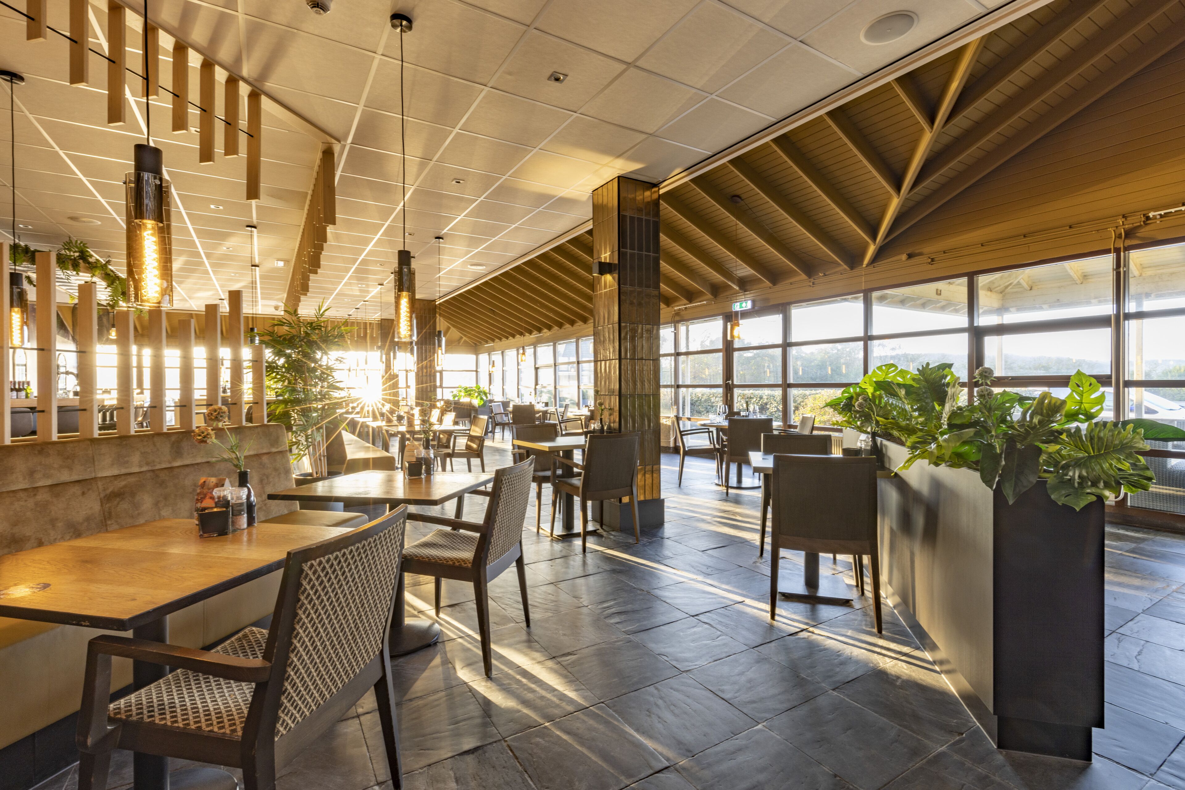 A spacious restaurant with high ceilings, large windows, and modern furniture.