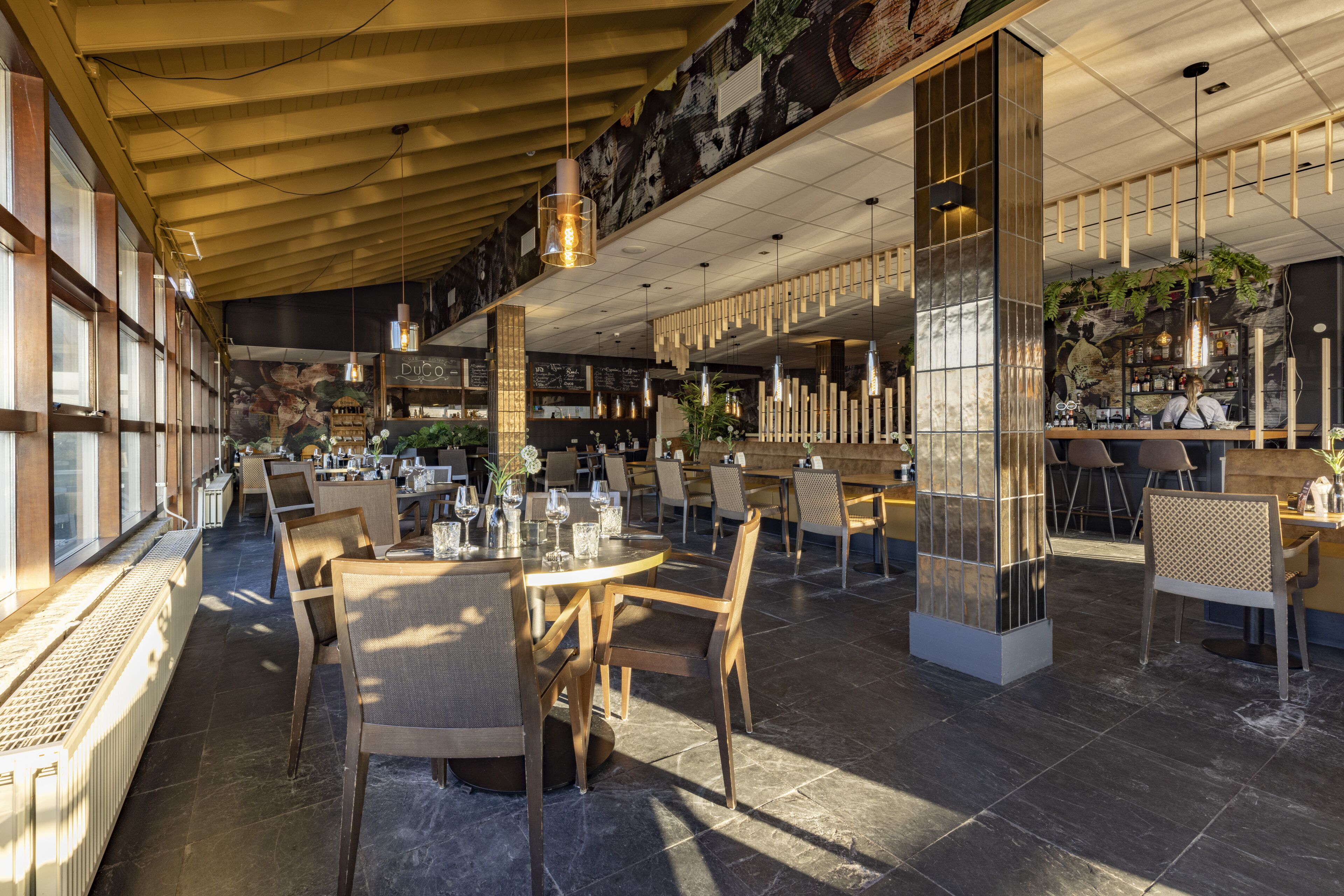 A spacious restaurant with high ceilings, modern lighting, and a variety of seating arrangements.