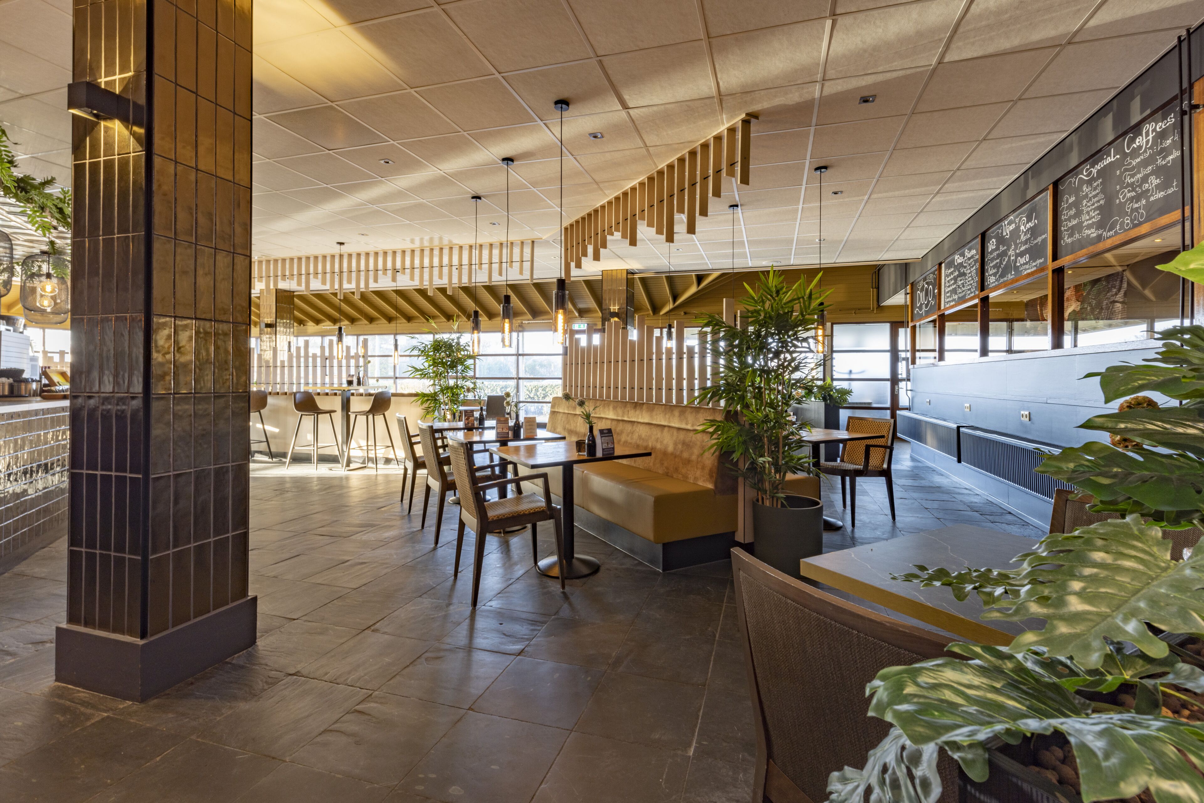 A modern restaurant with a high ceiling, wooden paneling, and a variety of seating options including tables and booths.