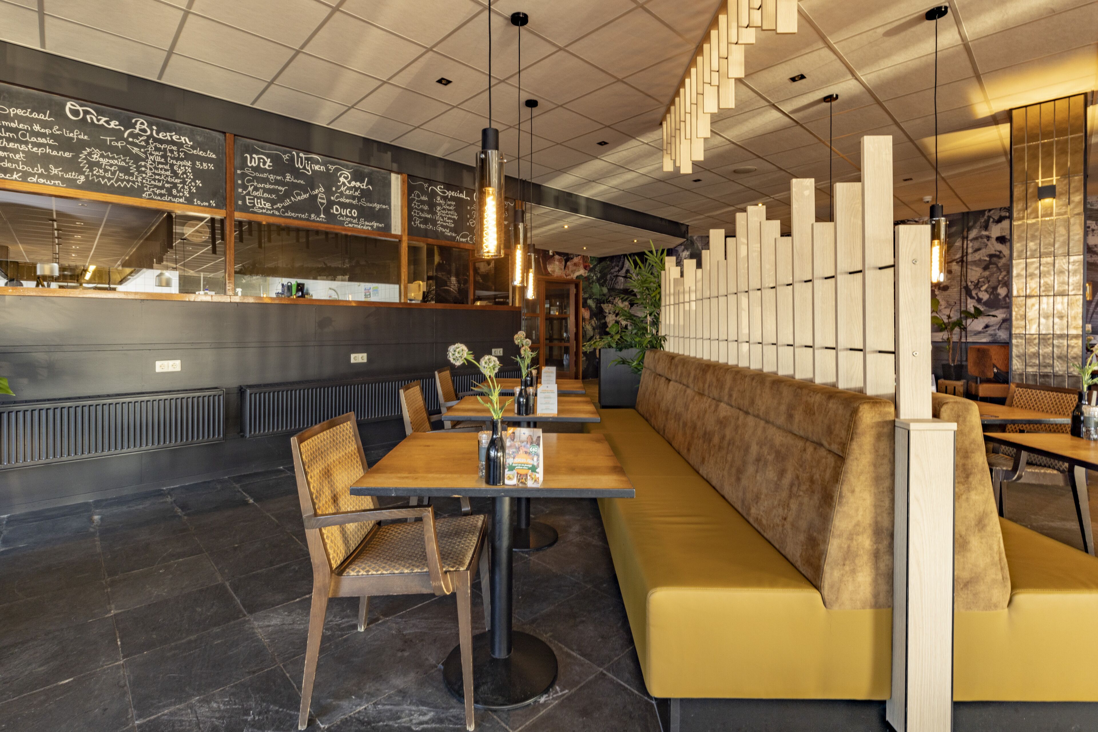 Ein Restaurant mit einer langen Theke, Holztischen und Sitzbereichen mit Polstern.