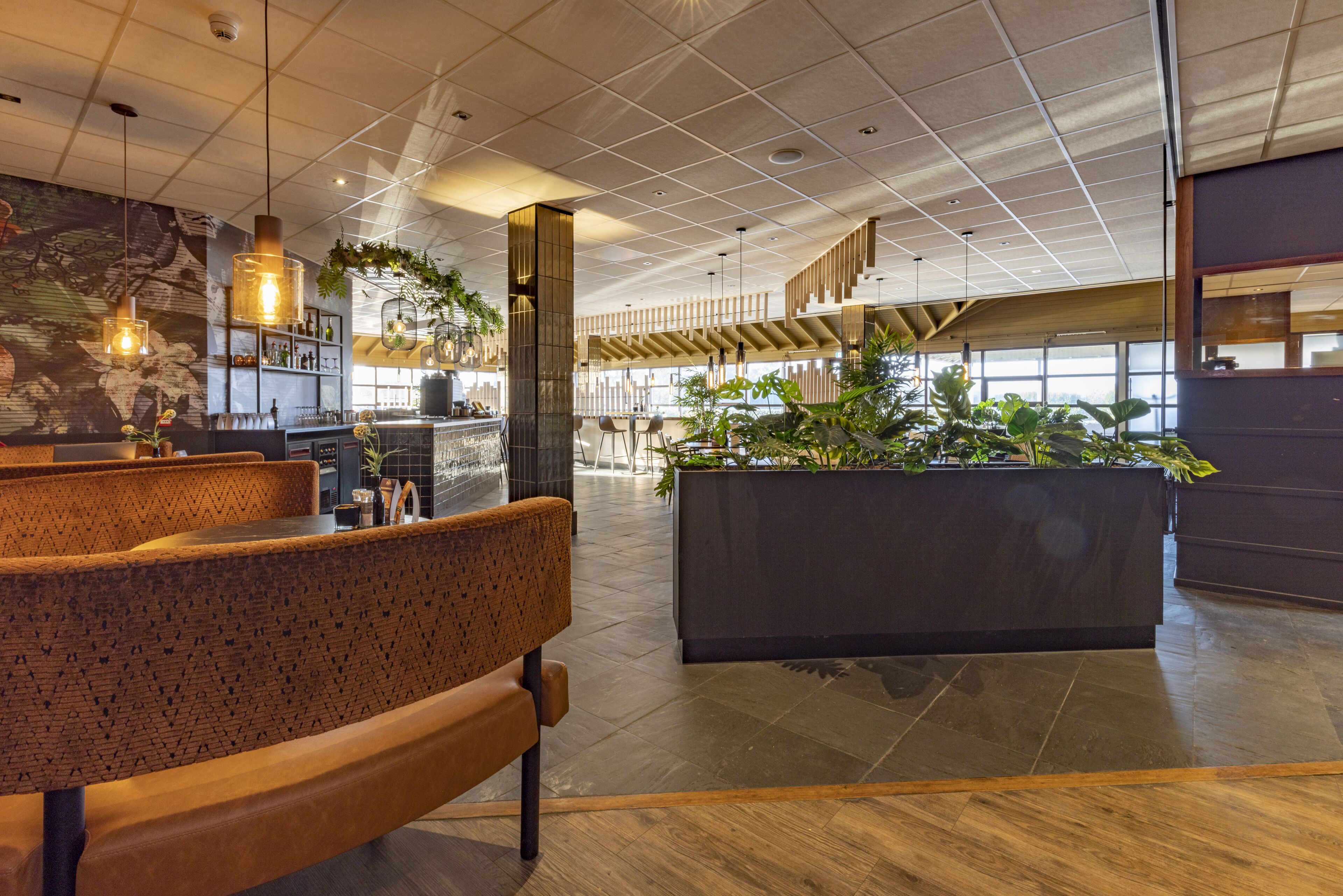 A modern interior with seating, a bar area, and a large planter with plants.