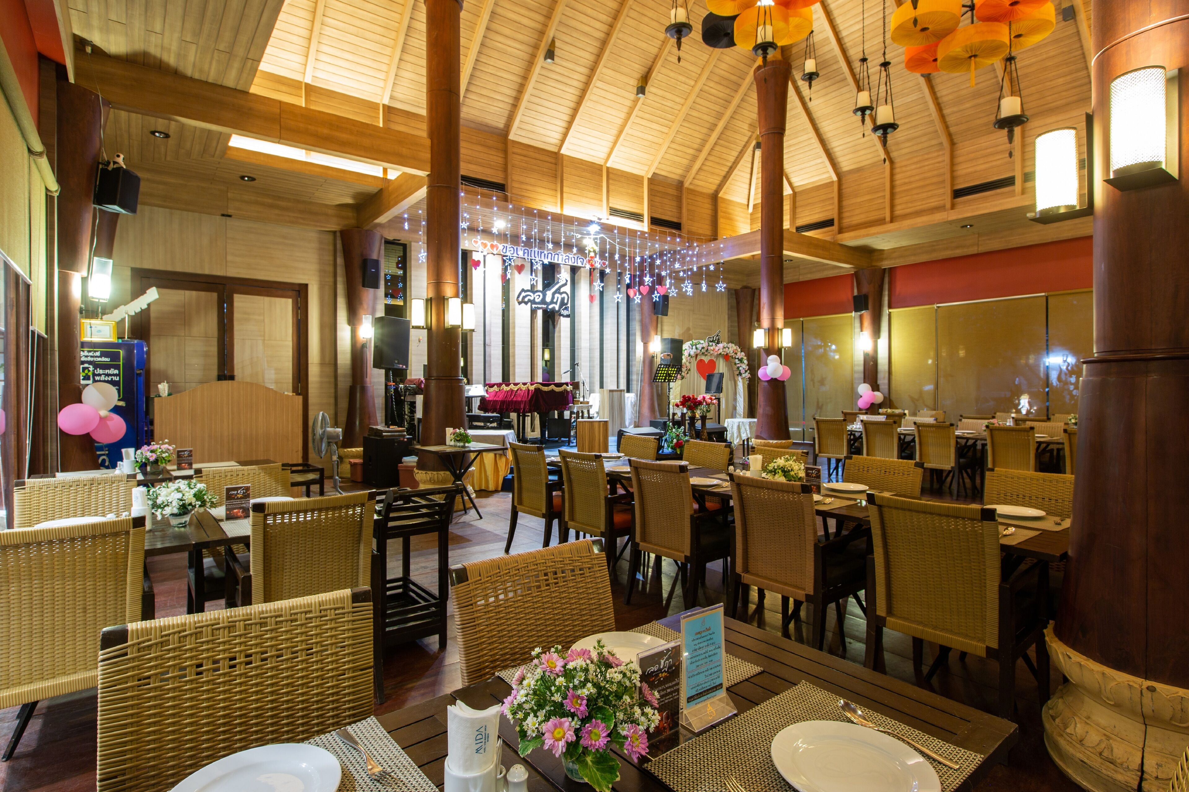 A restaurant with wooden ceiling, wicker furniture, and string lights.