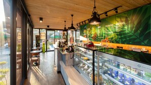A modern coffee shop interior with a wooden ceiling, glass display cases, and a menu board. - Mida Hotel Don Mueang Airport (Bangkok)