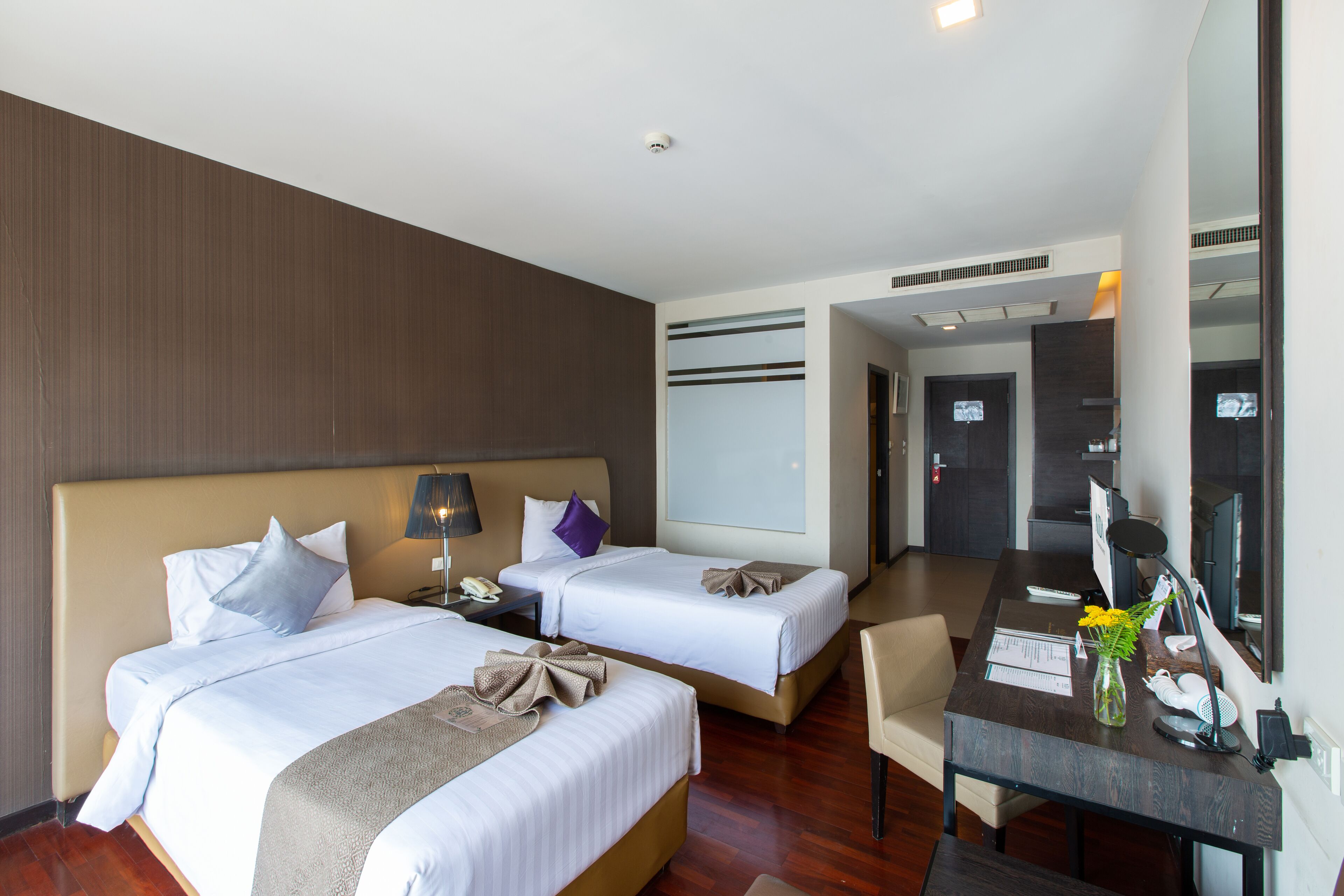 Habitación de hotel con dos camas, un escritorio, una silla y un espejo.