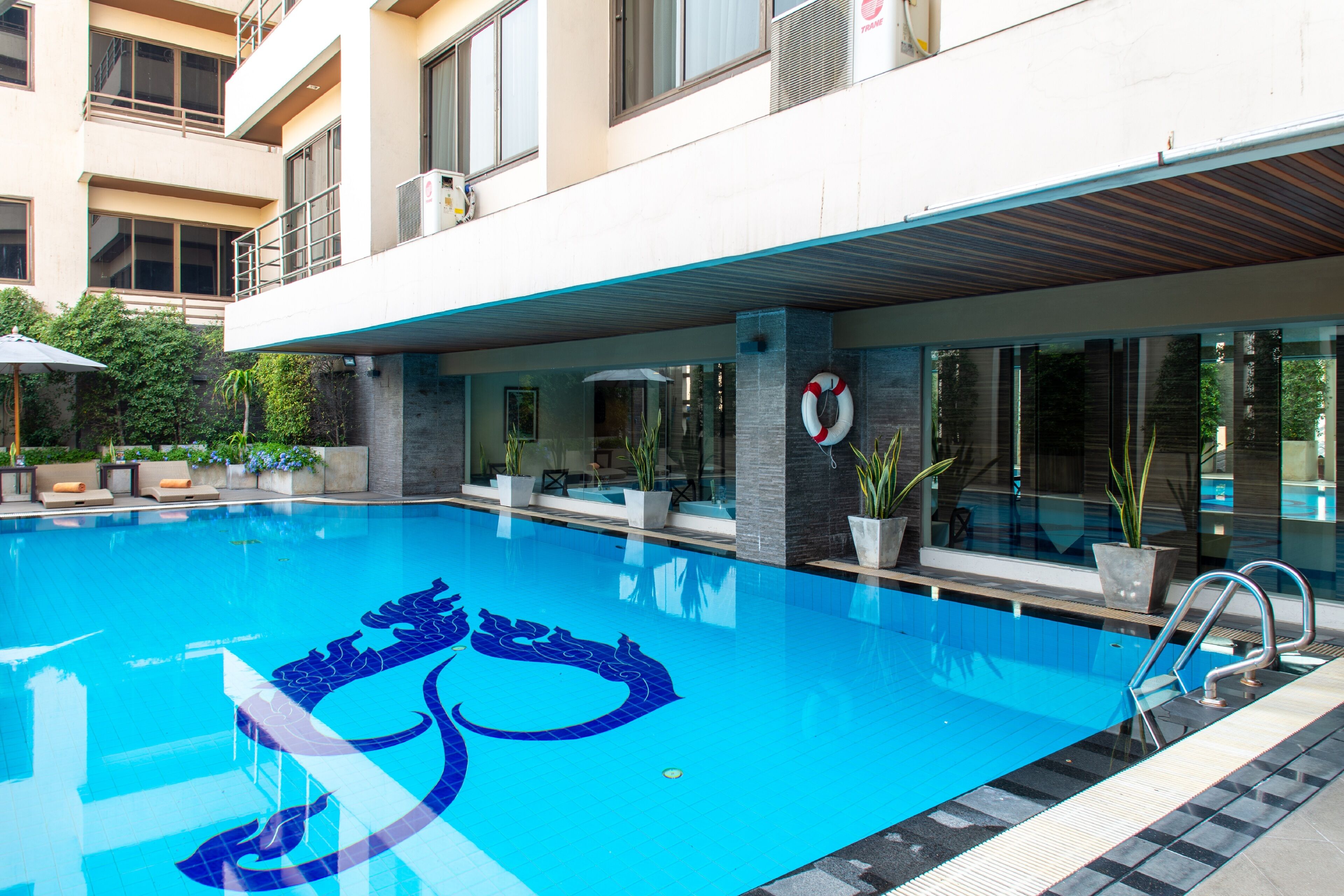 Una piscina con diseño de dragón, rodeada por un edificio con balcones y ventanas amplias.