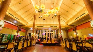 Un salón amplio con un alto techo de madera y filas de mesas y sillas, probablemente usado para eventos o reuniones.