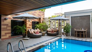 A swimming pool area with lounge chairs and umbrellas, a table, and potted plants. - Mida Hotel Don Mueang Airport (Bangkok)