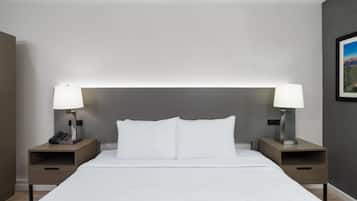 A neatly made bed with white linens, two bedside tables with lamps, and a framed picture on the wall.