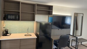 Una cocina compacta equipada con microondas, refrigerador y pileta.