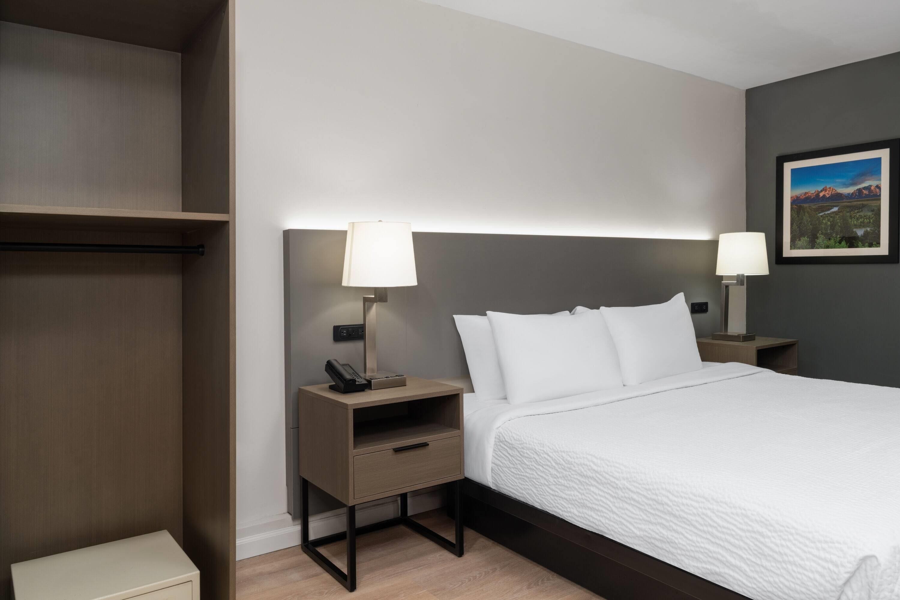 A hotel room with a large bed, two bedside tables with lamps, a small drawer, and a mounted telephone.