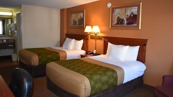 A hotel room with two beds, a desk, a chair, a lamp, and a mirror.