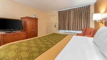 Une chambre d’hôtel avec un lit, une télévision, un bureau avec une lampe et une fenêtre avec des rideaux.