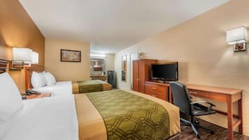 A hotel room with two beds, a desk, a chair, a television, and a kitchenette.