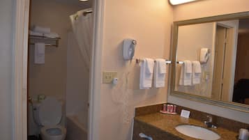 A bathroom with a toilet, a sink, a mirror, and a hairdryer on the wall.