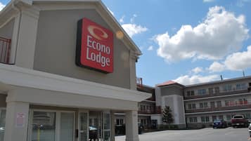 Un hôtel appelé Econo Lodge, avec une enseigne bien visible, un parking et un immeuble à plusieurs étages en arrière-plan.
