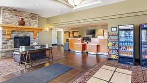 A lobby with a stone fireplace, a reception desk, a television, and vending machines.