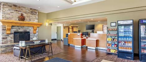A lobby with a stone fireplace, a reception desk, a television, and vending machines.